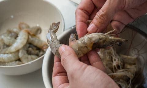 photo of chef de-shelling raw prawns